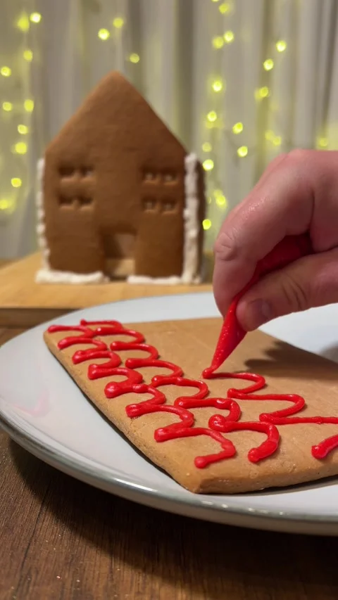 Female hand with draws red wave pattern on gingerbread cookie Stock Footage 340427923