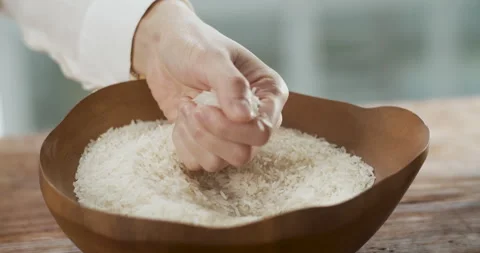 Female hand feeling clean raw rice and rice slide down to a wooden bowl 動画素材 204844741