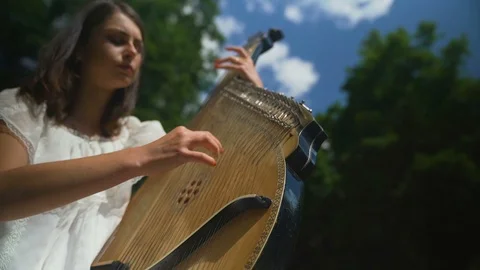 The female hand gently touches the strings of the bandura at waterfall Stock Footage 94969479