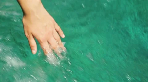 A female hand glides through turquoise waters Stock Footage
