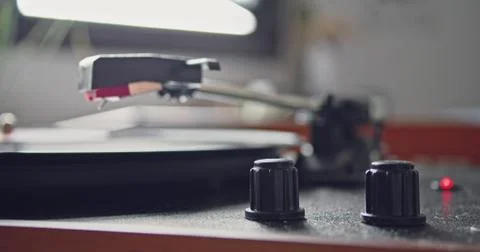 Female hand going down headshell of vintage portable record player and start Stock Photos