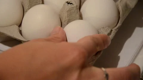 A female hand grabs an egg from the corner of an egg carton to use for baking co Vídeo Stock 68139802