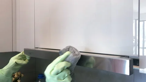 Female hand in green gloves pulls out kitchen hood and wipes it with a rag Stock Footage 231511214