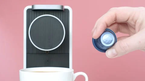 Female hand hold capsule for coffee machine on pink background. Stock Footage 269491753