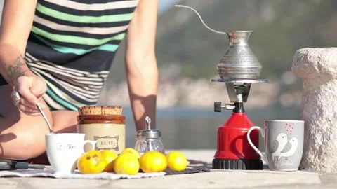 Female hand hold spoon and stir hot coffee inside cezve at picnic in Montenegro Stock Footage 165079059