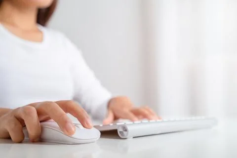 Female hand holding computer wireless mouse and working on a computer keyboar Stock Photos