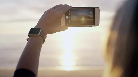 Female Hand Holding iPhone Capturing Sunset Oregon Coast Ocean Beach Golden Hour Vídeo Stock 128543309