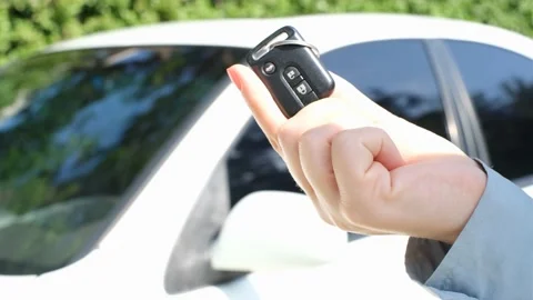 Female hand holding key against the background of a white car. Stock Footage 201642453
