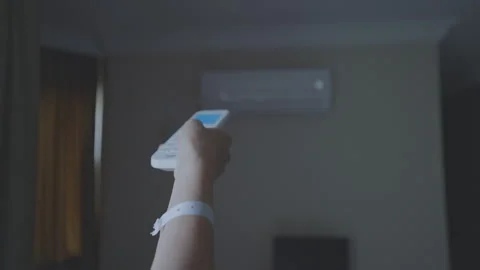 Female hand holding remote control aimed at air conditioner Stock Footage 249697255