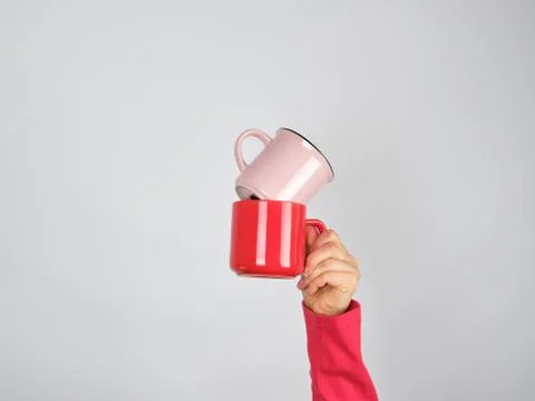 Female hand holding a stack of ceramic mugs Stock Photos