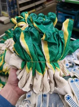 Female hand holding a stack of rubberized gloves for gardening in hardware st Stock Photos