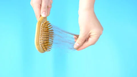Female hand holds a comb with fallen hair close-up on blue background, hair loss Stock Footage 213767189