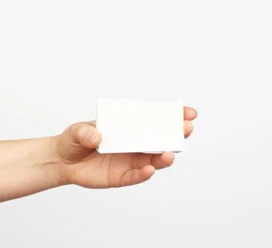 Female hand holds a stack of white rectangular paper business cards on a whit Stockfoto's