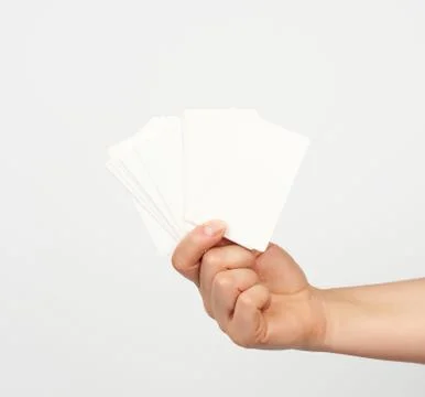 Female hand holds a stack of white rectangular paper business cards on a whit 스톡 사진
