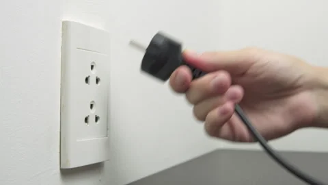 Female hand inserting a black electrical plug into outlet Stock Footage 314776121