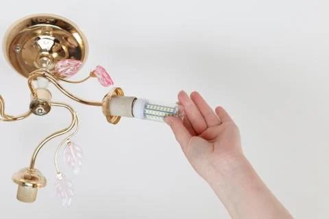 Female hand inserts a light bulb into the threaded socket. Installation of ho Stock Photos