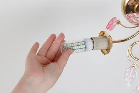 Female hand inserts a light bulb into the threaded socket. Installation of ho Stock Photos
