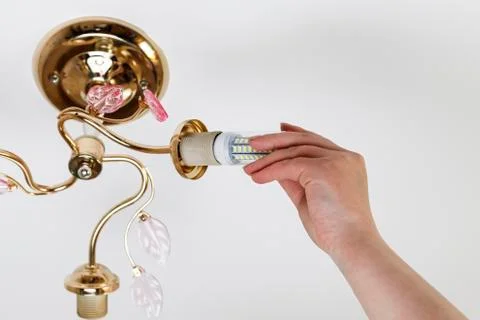 Female hand inserts a light bulb into the threaded socket. Installation of ho Stock Photos