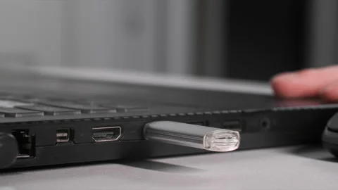 Female hand inserts USB flash drive into laptop to transfer information, close Stock Footage 240858312
