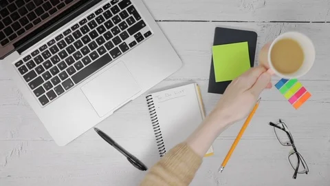 Female hand lifting a cup of tea at a wooden desk with a laptop Stock Footage 121892364