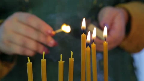 A female hand lights candles on Hanukkah in a beautiful candlestick. 库存影片 116646053