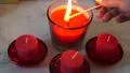 Female hand with long nails holds long match to light four red candles HD Footage