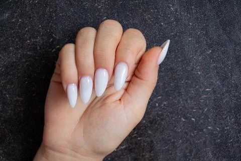 Female hand with long sharp white manicure on black background Foto stock