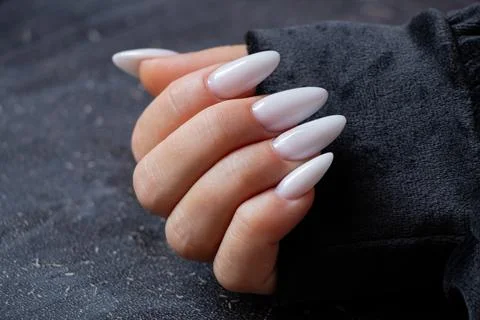 Female hand with long sharp white manicure on black background Stock Photos