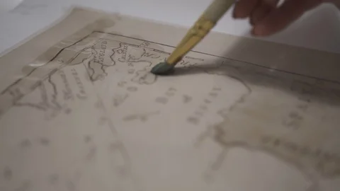 Female hand make aged map with paint brush and transparent watercolor, close-up Stock-Footage 94761984