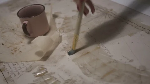 Female hand make aged map with paint brush and transparent watercolor, close-up Stock-Footage 94764910