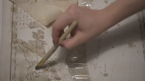 Female hand make aged map with paint brush and transparent watercolor, close-up Stock-Footage 94765604