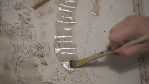 Female hand make aged map with paint brush and transparent watercolor, close-up Stock-Footage 94765642