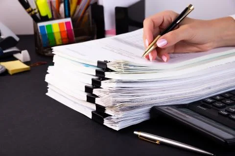 Female hand makes notes on a stack of documents in the office 写真素材