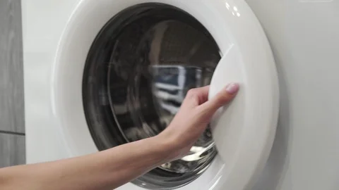 Female hand with married ring put GREEN SNEAKERS in laundry machine. Loading Video stock 128054348
