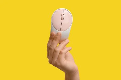Female hand with modern wireless computer mouse on yellow background Stock Photos