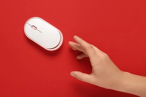 Female hand with modern wireless computer mouse on red background Stock Photos
