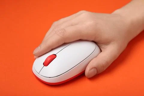 Female hand with modern wireless computer mouse on orange background Stock Photos