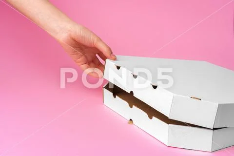 Female hand opening pizza delivery box on pink background Stock Photos
