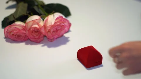 Female hand opens a box with a gold ring on the table near the roses Stock Footage 100289746