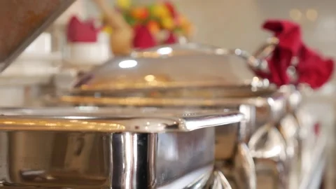 A female hand opens a heated serving container on a restaurant buffet line Stock Footage 332416565