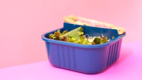 Female hand opens the lid in lunch box with food on pink background. Stock Footage 243548299