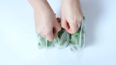 Female hand opens the package with frozen peas on green background, selective Stock Footage 166019826
