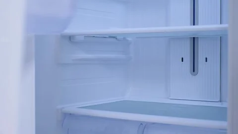 A female hand opens refrigerator with empty shelves, front view. Stock Footage 320990273