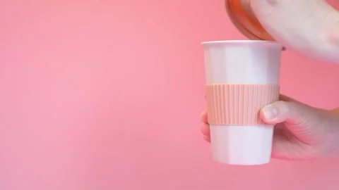 Female hand opens silicone lid from a ceramic coffee cup on a pink background. Stock Footage 243548330