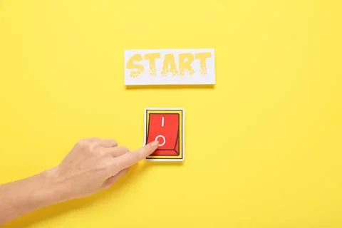 Female hand with paper switch button and word START on yellow background Stock Photos