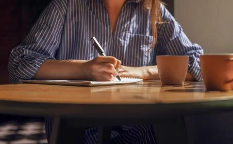 Female hand with pen taking notes, writing plans in diary on wood table with  Stock Photos
