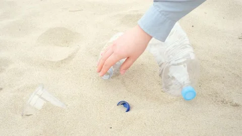 Female hand pick up plastic bottles on the beach close-up. Stock Footage 201125869