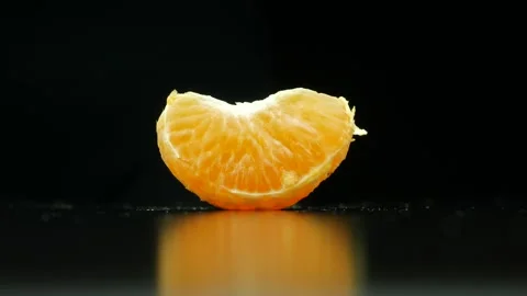 Female hand picking up mandarin slice from a black table. Stock Footage 159001509