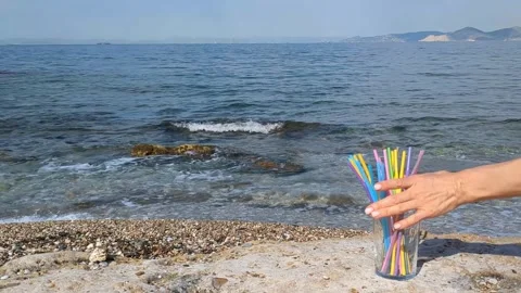 Female hand picks up plastic straws from glass and puts back biodegradable Stock Footage 310367253
