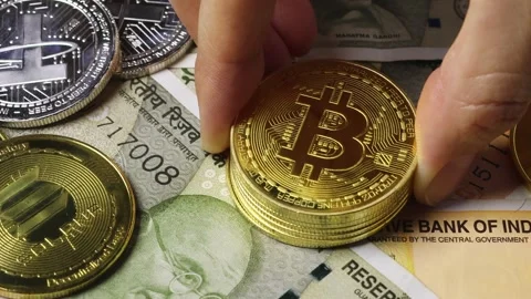 Female hand places a stack of Bitcoin coins upon Indian rupee banknotes Stock Footage 318056478